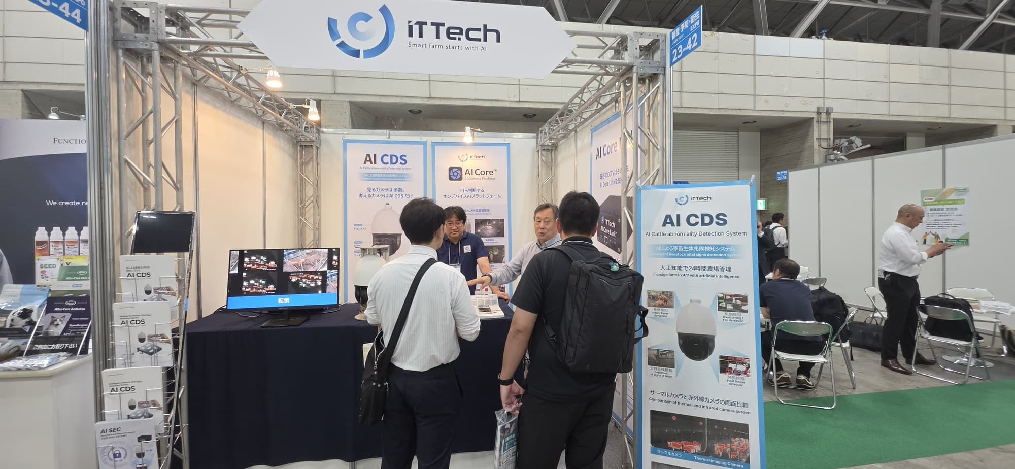 iTTech 간판과 AI CDS 배너가 걸린 전시 부스에서 직원이 모니터 앞 방문객에게 제품을 설명하고 있다